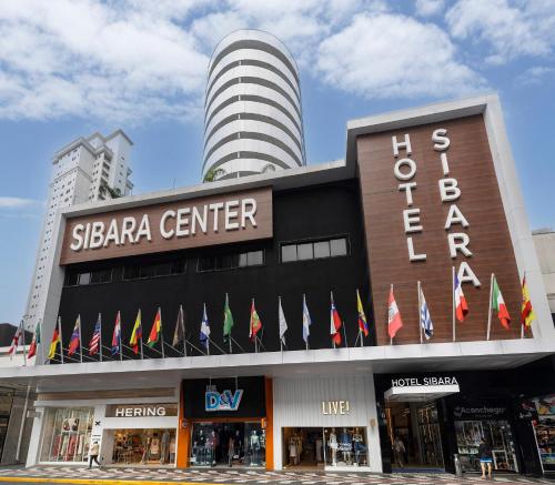 Fachada do Hotel Sibara com várias bandeiras na entrada e torre redonda ao fundo